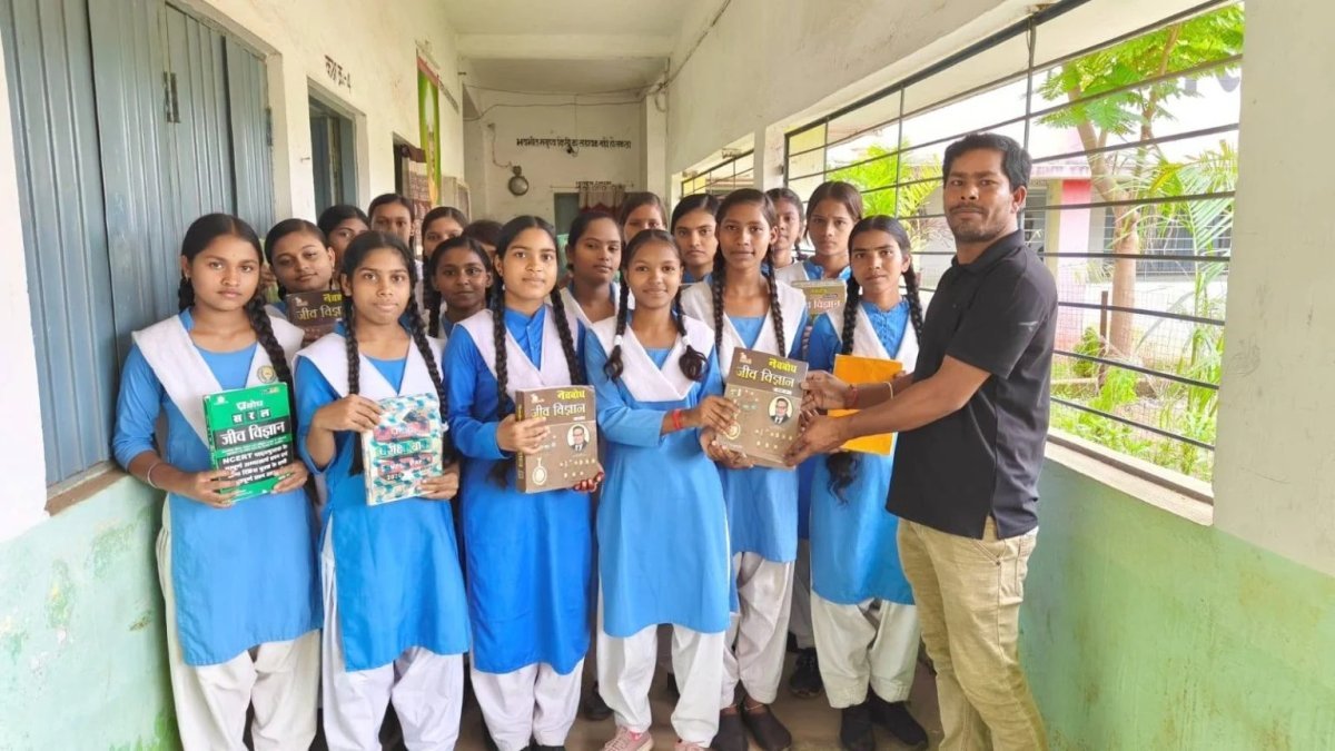 छात्राओं को पुस्तकें वितरित करते शिक्षक कृष्ण कुमार कुर्रे
