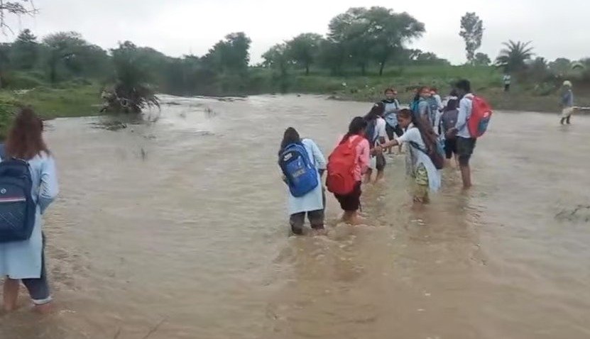 नदी पार करते स्कूली बच्चे